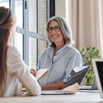 VA Meltdown: 75% Claims Botched Smiling woman with gray hair talking in a modern office