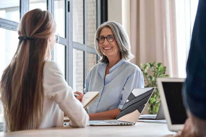 shutterstock_1954711978 Smiling woman with gray hair talking in a modern office