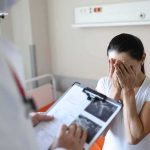 Shocking VERDICT! Mom Deemed Not Responsible Woman covering her face while doctor holds a clipboard in a hospital room