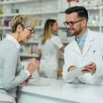 Drug Giants Blink – Medicaid Plays Hardball Pharmacist assists customer at pharmacy counter
