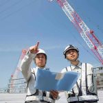 Grisly Ambush Filmed—Media Shrugs Two construction workers reviewing plans at a site with cranes
