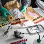 New DNA Result Upends 40 Year Murder Case Forensic technician handling evidence bags on a lab table