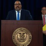 Sinaloa Officials Exposed: Bribery Blueprint Unveiled! Man speaks at podium with New York County District Attorney seal