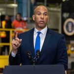 Senate Democrat Makes Explosive Midterm Election Claim Cory Booker speaks at a podium, with Caraun Reid in the background