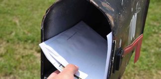 Hand retrieving mail from an open rural mailbox