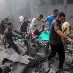 Rescuers carry an injured person on a stretcher through rubble