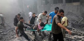 Rescuers carry an injured person on a stretcher through rubble