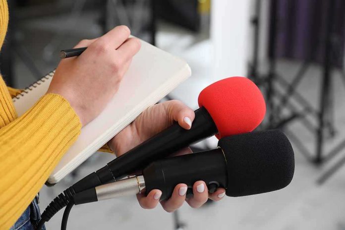 shutterstock_2431198207-4 Journalist holding two microphones while writing in a notebook