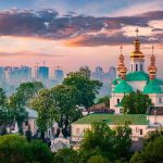 Orthodox church with green domes and golden spires at sunset