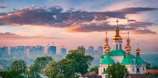 Orthodox church with green domes and golden spires at sunset
