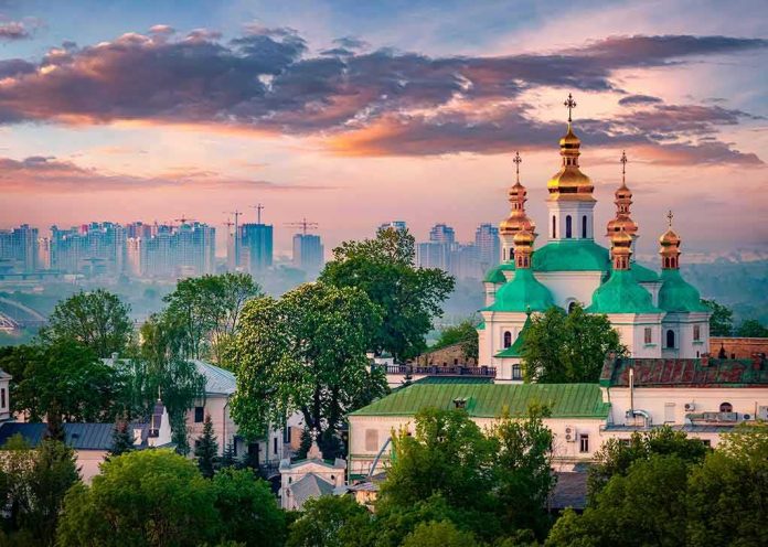 Orthodox church with green domes and golden spires at sunset