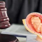 Aborted Baby’s Estate Awarded $200K Judge's gavel beside a fetal model of a pregnant uterus