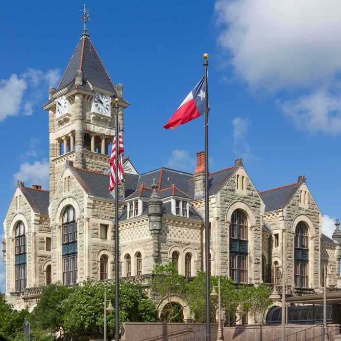 shutterstock_288707069 Historic stone courthouse with clock tower and flags