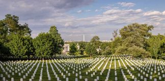 Rows of white headstones in a cemetery under a partly cloudy sky
