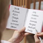 The Shameful Double Life Of An Elementary Teacher Hands holding a notebook with baby name lists near a crib