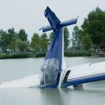 Hear Tom Tiffany’s First Words After Plane Crash A submerged airplane partially in a lake with trees in the background