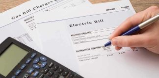 hand reviewing utility bills with calculator on desk