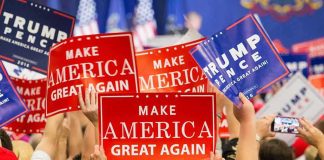 Crowd holding red and blue campaign signs at a political rally