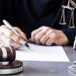 She Called Her 2-Year-Old-Son “The Devil” And Strangled Him Judge writing at desk with gavel and Lady Justice statue