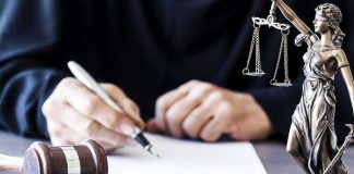 She Called Her 2-Year-Old-Son “The Devil” And Strangled Him Judge writing at desk with gavel and Lady Justice statue