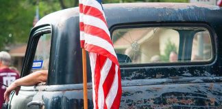 American flag on the bed of a weathered vintage pickup truck
