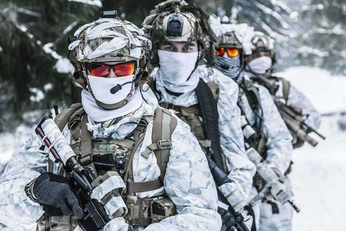 shutterstock_586083506 Soldiers in white winter camouflage gear standing in a snowy forest