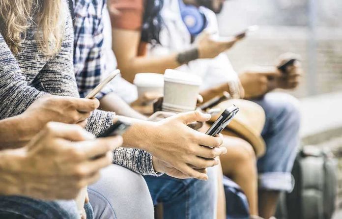 shutterstock_794117806-1 Group of people sitting and using smartphones