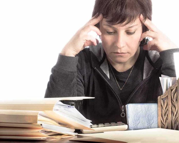 shutterstock_83248873 Person stressed while working with paperwork and calculator