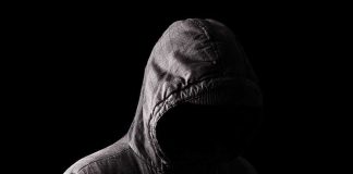 NFL Sideline Star Takes Aim at Somali GANGS Hooded figure in shadow on black background