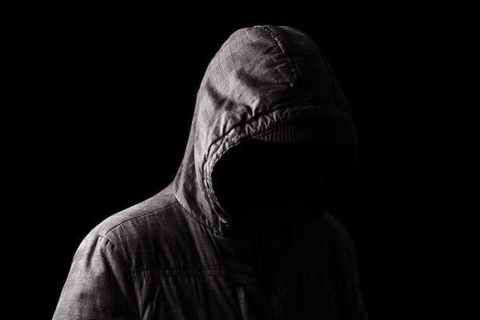 Hooded figure in shadow on black background