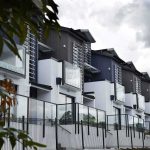 New Rule Targets Wall Street Buying Up HOMES Modern townhouse row with glass balconies and metal accents under cloudy sky