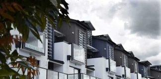 New Rule Targets Wall Street Buying Up HOMES Modern townhouse row with glass balconies and metal accents under cloudy sky