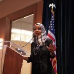 Ilhan Omar’s House Seat in SERIOUS DANGER Ilhan Omar speaking at a podium with a microphone