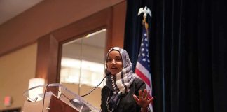 Ilhan Omar’s House Seat in SERIOUS DANGER Ilhan Omar speaking at a podium with a microphone