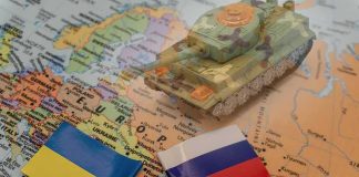 Toy tank on a map with Ukraine and Russia flags