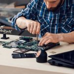 Palantir CEO Warns Who Will SURVIVE the AI Era Technician repairing a laptop motherboard at a workbench