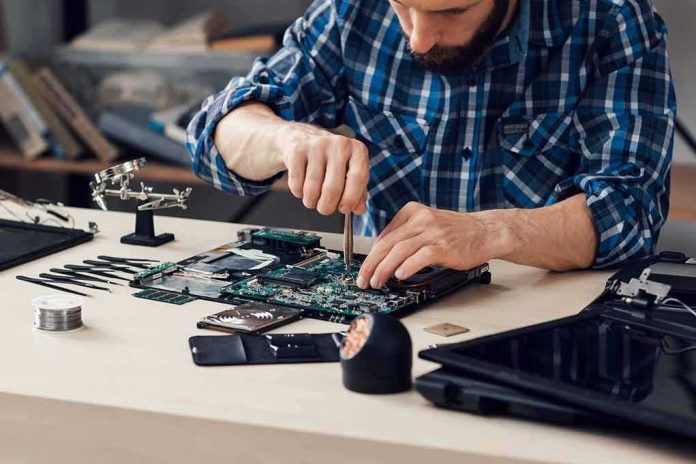 shutterstock_521671885 Technician repairing a laptop motherboard at a workbench