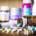 Medicaid Stops Paying for Kids’ Gender TRANSITIONS Medicine pills and syringe on table with brown bottle